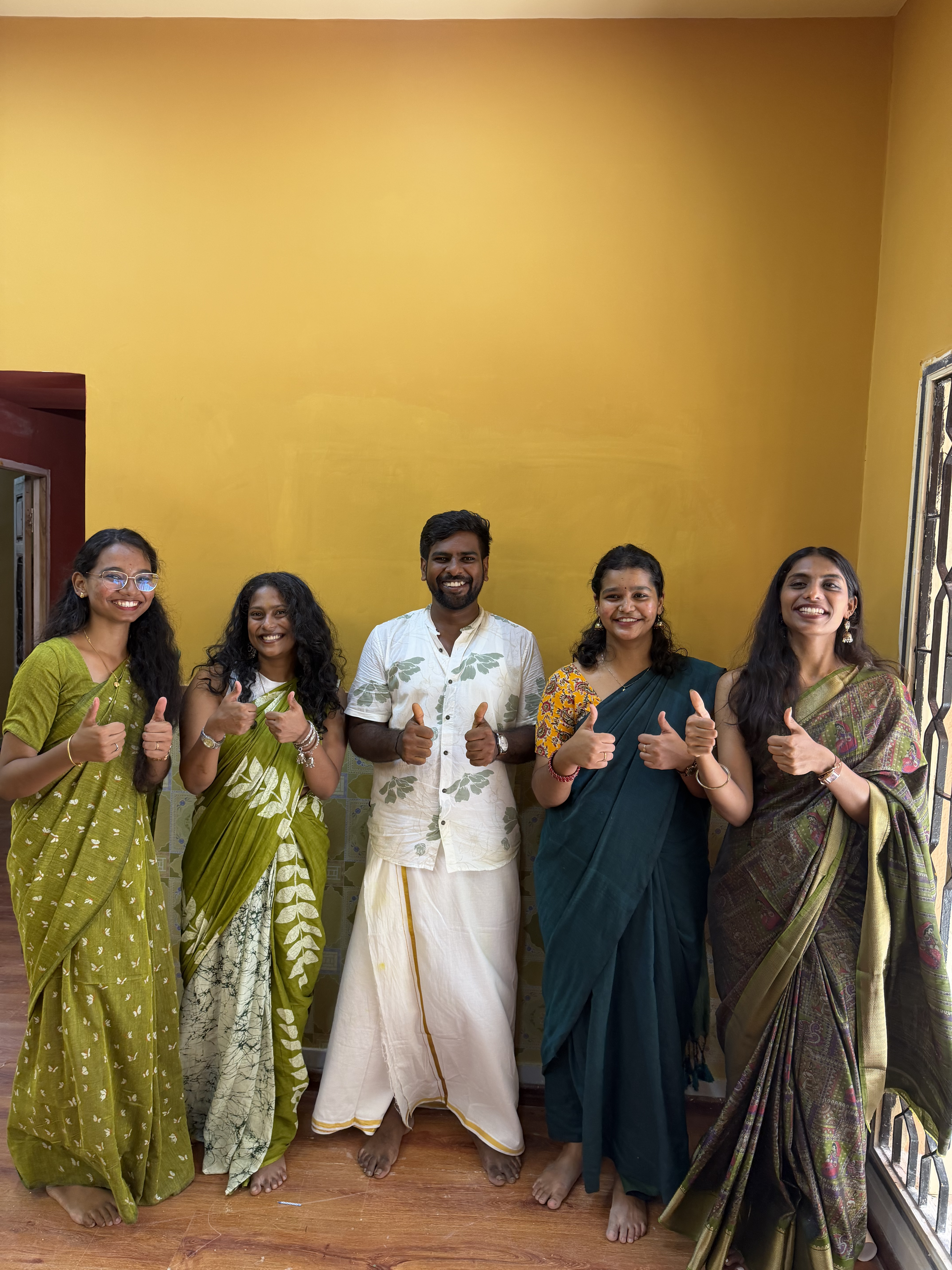 All Team Members stading infront of yellow wall and giving thumbsup pose